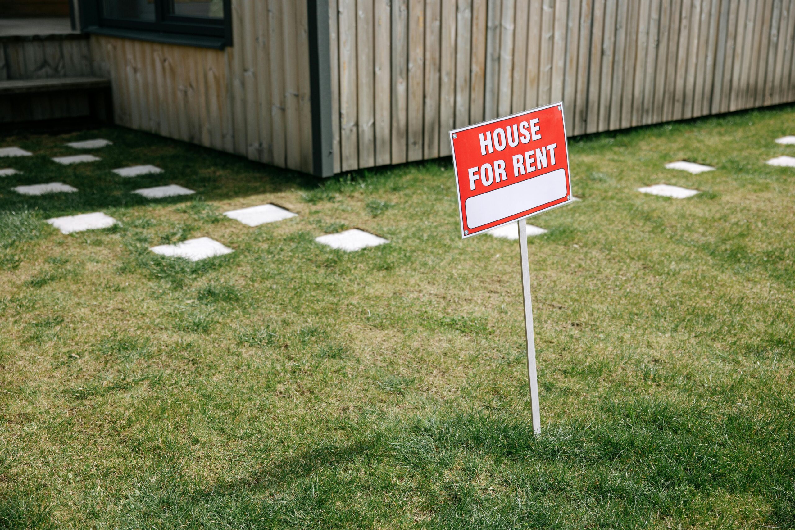 Red and White House for rent sign board on the Lawn Grass