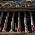 New York Stock Exchange building on Wall Street with American flags displayed, WNews stock photo taken April 2023.