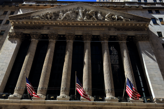 New York Stock Exchange building on Wall Street with American flags displayed, WNews stock photo taken April 2023.