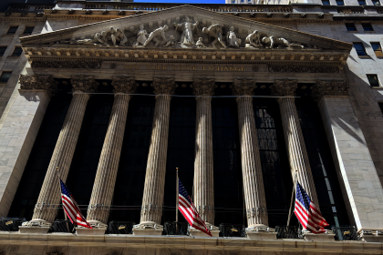 New York Stock Exchange building on Wall Street with American flags displayed, WNews stock photo taken April 2023.