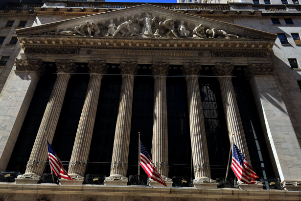 New York Stock Exchange building on Wall Street with American flags displayed, WNews stock photo taken April 2023.