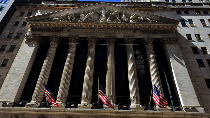 New York Stock Exchange building on Wall Street with American flags displayed, WNews stock photo taken April 2023.